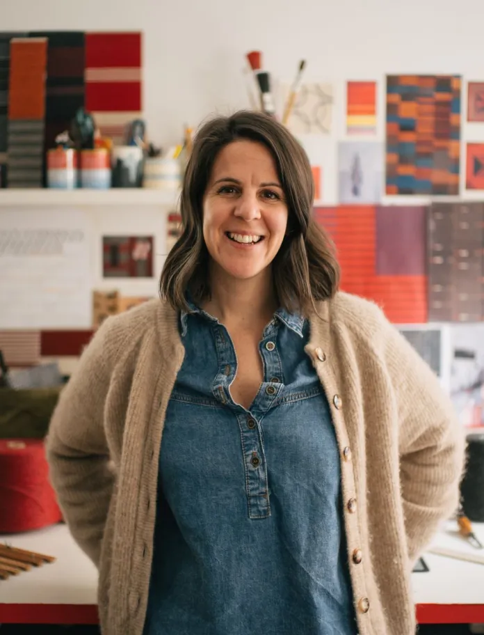 L'artiste textile galloise Llío James debout à son bureau dans son atelier.