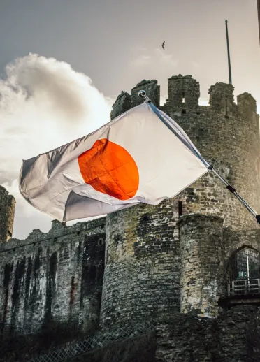 Le drapeau japonais flottant par une journée ensoleillée devant la vue majestueuse du château historique de Conwy au Pays de Galles, jumelé avec le château de Himeji au Japon.