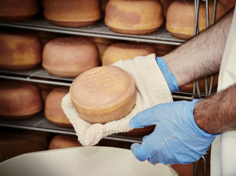 Un employé tient une meule de fromage.