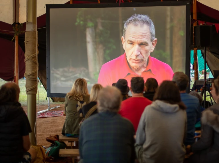 人々が座ってプロジェクタースクリーンで映画を観ている