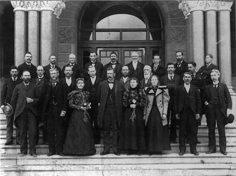 Photographie en noir et blanc des membres du Sénat de l'Utah - un groupe d'hommes et de femmes debout sur les marches d'un vieux bâtiment.