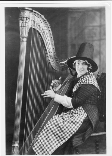 Une femme assise porte le costume traditionnel gallois et joue de la harpe.