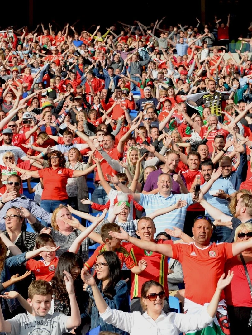 Une foule de personnes à un match de football chantant l'hymne national.