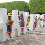Bunt gekleidete Menschen zwischen großen Hay-Festival-Buchstaben.