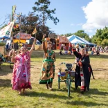 Trois personnes habillées en costumes de festival éclatants levant les bras pour saluer